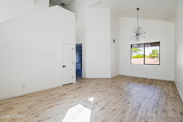 185 E Calle Zavala, Tucson, AZ 85704 - empty room with high vaulted ceiling, a chandelier, wood finished floors, and baseboards