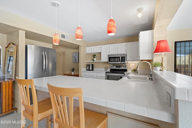 7302 E Rocky Creek Pl, Tucson, AZ 85750 - kitchen with stainless steel appliances, a sink, tile countertops, a peninsula, and white cabinets