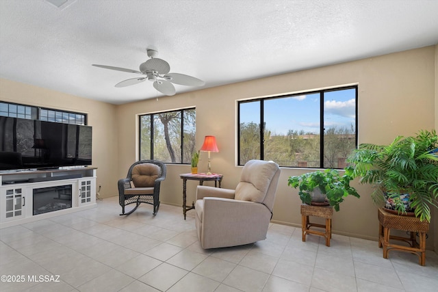 7302 E Rocky Creek Pl, Tucson, AZ 85750 - living room with a ceiling fan, a textured ceiling, a glass covered fireplace, light tile patterned floors, and baseboards