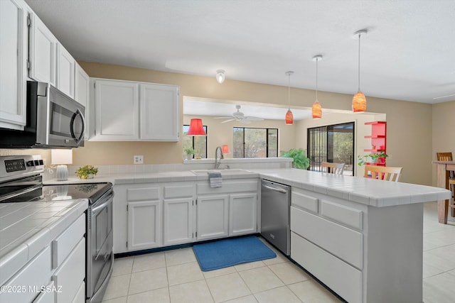 7302 E Rocky Creek Pl, Tucson, AZ 85750 - kitchen featuring stainless steel appliances, tile counters, a peninsula, a sink, and ceiling fan
