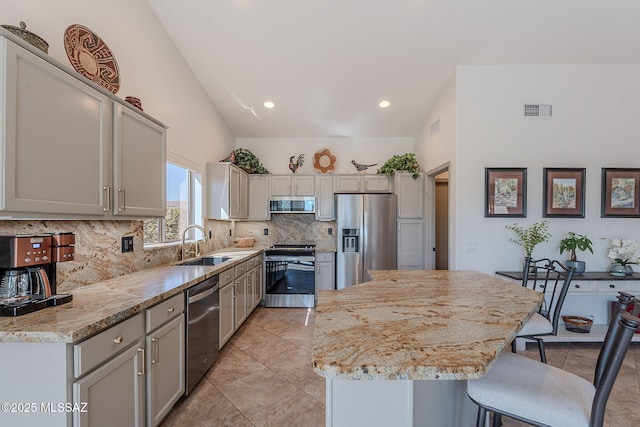 2136 E Desert Fox Dr, Green Valley, AZ 85614 - kitchen featuring appliances with stainless steel finishes, lofted ceiling, a kitchen breakfast bar, a kitchen island, and tasteful backsplash