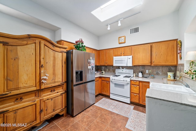 7466 E Placita Del Misterio, Tucson, AZ 85715 - kitchen with white appliances, a sink, a skylight, brown cabinets, and tile patterned flooring