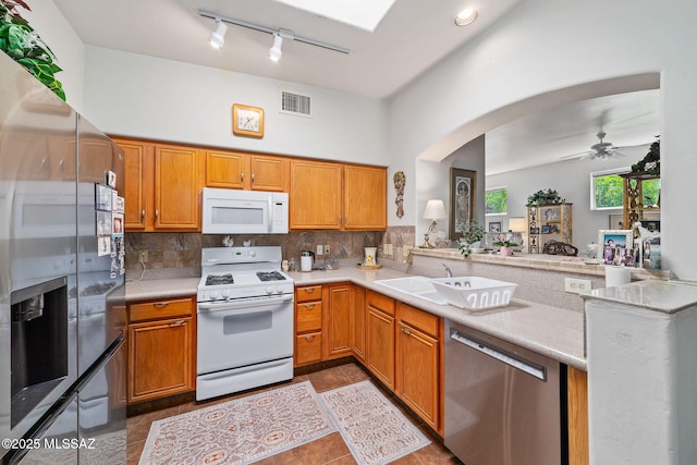 7466 E Placita Del Misterio, Tucson, AZ 85715 - kitchen featuring appliances with stainless steel finishes, arched walkways, track lighting, and backsplash