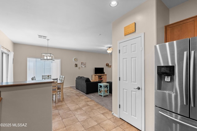 77 N Mail Station Ln, Sahuarita, AZ 85629 - kitchen with stainless steel refrigerator with ice dispenser, light tile patterned floors, ceiling fan, brown cabinetry, and pendant lighting