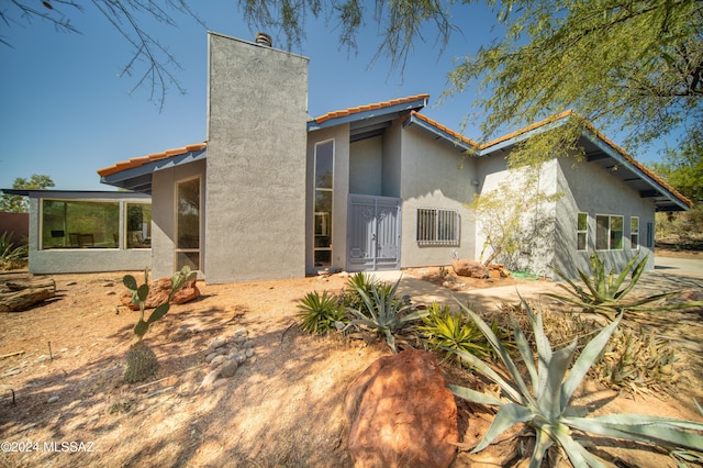 5617 N Camino Del Conde, Tucson, AZ 85718 - back of house featuring a chimney, stucco siding, and a sunroom