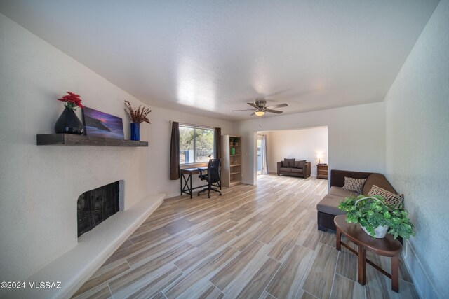 5617 N Camino Del Conde, Tucson, AZ 85718 - living room featuring a fireplace with raised hearth, a ceiling fan, and wood finished floors