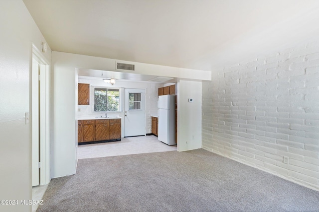 341 W Camino Penasco Apt B, Green Valley, AZ 85614 - unfurnished living room with a sink, light carpet, and brick wall