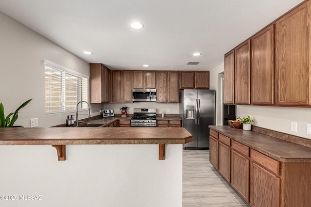 1257 W Calle Libro Del Retrato, Sahuarita, AZ 85629 - kitchen featuring appliances with stainless steel finishes, a sink, dark countertops, a kitchen breakfast bar, and a peninsula
