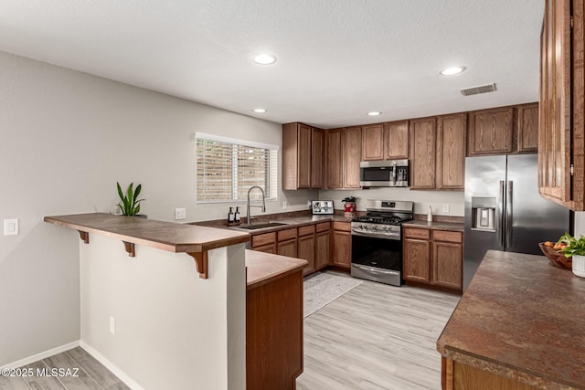 1257 W Calle Libro Del Retrato, Sahuarita, AZ 85629 - kitchen with stainless steel appliances, a sink, a peninsula, dark countertops, and a breakfast bar