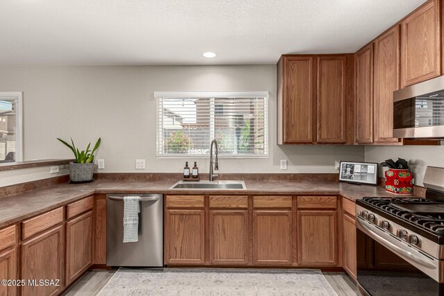 1257 W Calle Libro Del Retrato, Sahuarita, AZ 85629 - kitchen featuring appliances with stainless steel finishes, a sink, dark countertops, brown cabinetry, and recessed lighting