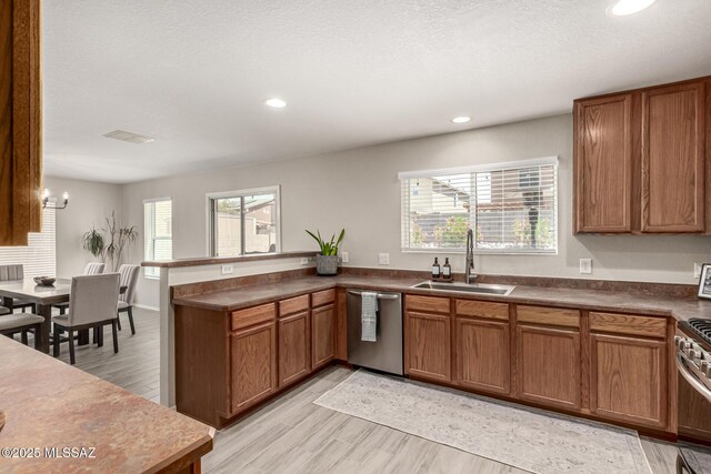 1257 W Calle Libro Del Retrato, Sahuarita, AZ 85629 - kitchen with a sink, appliances with stainless steel finishes, brown cabinetry, recessed lighting, and a peninsula
