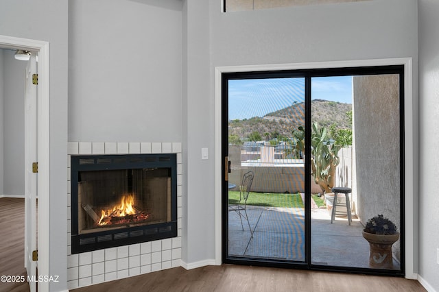 4996 N Valle Rd, Tucson, AZ 85750 - doorway to outside featuring wood finished floors, a mountain view, a warm lit fireplace, and baseboards