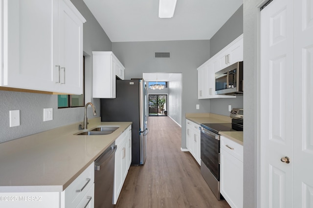 4996 N Valle Rd, Tucson, AZ 85750 - kitchen featuring stainless steel appliances, a sink, wood finished floors, white cabinetry, and light countertops