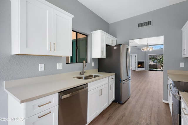 4996 N Valle Rd, Tucson, AZ 85750 - kitchen featuring appliances with stainless steel finishes, a sink, white cabinetry, wood finished floors, and a chandelier