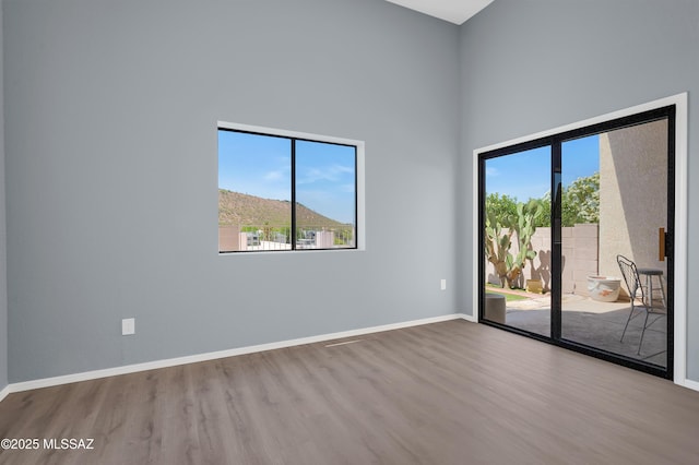 4996 N Valle Rd, Tucson, AZ 85750 - empty room featuring wood finished floors, plenty of natural light, a high ceiling, and baseboards