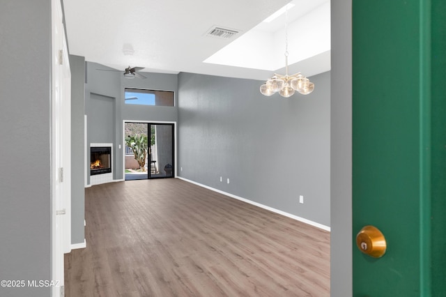 4996 N Valle Rd, Tucson, AZ 85750 - unfurnished living room featuring wood finished floors, baseboards, a warm lit fireplace, a chandelier, and a ceiling fan