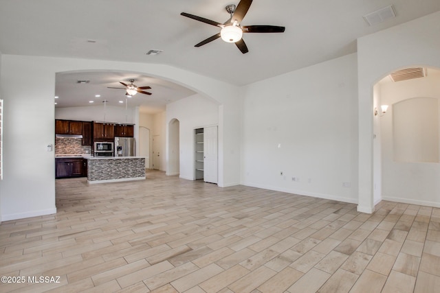 9016 W Birchover Dr, Marana, AZ 85653 - unfurnished living room with a ceiling fan, arched walkways, light wood-style floors, baseboards, and recessed lighting