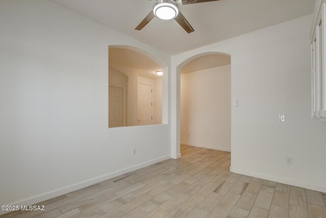 9016 W Birchover Dr, Marana, AZ 85653 - spare room featuring a ceiling fan, arched walkways, light wood-style flooring, and baseboards