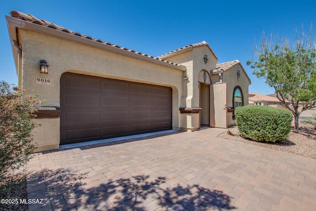 9016 W Birchover Dr, Marana, AZ 85653 - mediterranean / spanish-style home featuring stucco siding, a garage, a tiled roof, and driveway