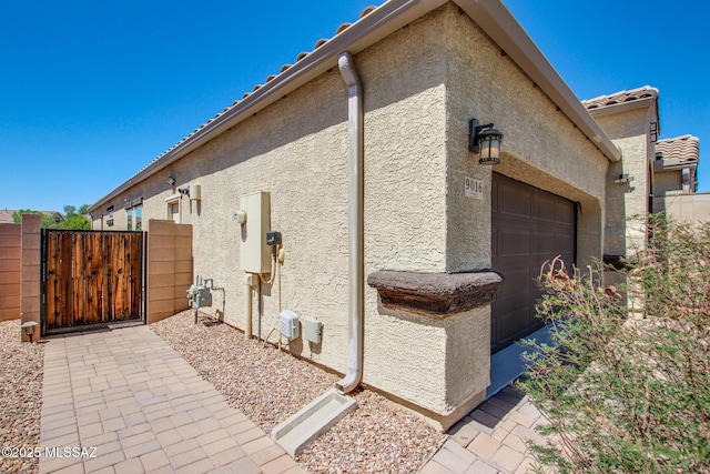 9016 W Birchover Dr, Marana, AZ 85653 - view of side of property featuring stucco siding, a garage, and a gate