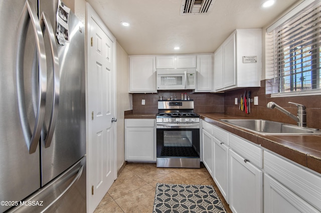 1410 W Sonora St, Tucson, AZ 85745 - kitchen featuring stainless steel appliances, a sink, dark countertops, white cabinets, and light tile patterned floors