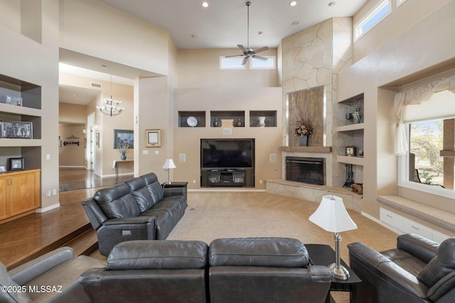 4141 W Camino Del Norte, Tucson, AZ 85742 - living area featuring built in shelves, plenty of natural light, a ceiling fan, a high end fireplace, and a towering ceiling