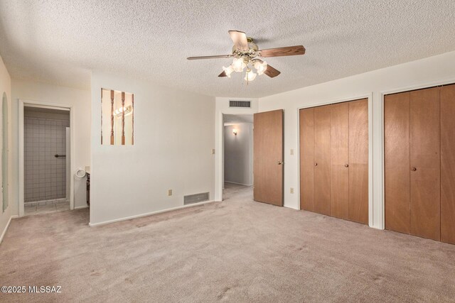555 E Rudasill Rd, Tucson, AZ 85704 - unfurnished bedroom with two closets, carpet floors, a textured ceiling, ensuite bath, and a ceiling fan