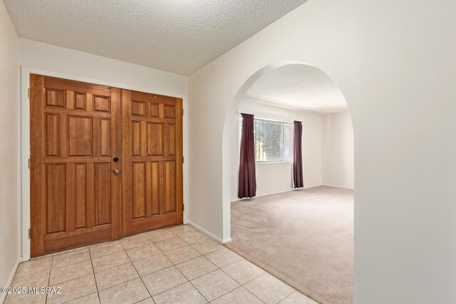 555 E Rudasill Rd, Tucson, AZ 85704 - foyer entrance featuring arched walkways, a textured ceiling, light tile patterned floors, and light carpet