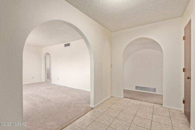 555 E Rudasill Rd, Tucson, AZ 85704 - spare room featuring light colored carpet, arched walkways, a textured ceiling, and light tile patterned floors