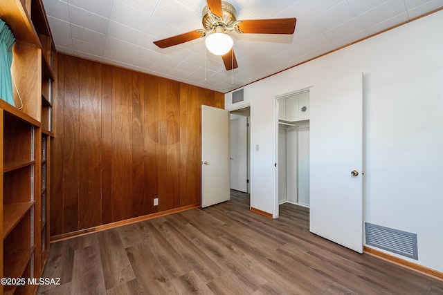 3225 E Elida St, Tucson, AZ 85716 - unfurnished bedroom featuring wooden walls, wood finished floors, baseboards, and ceiling fan