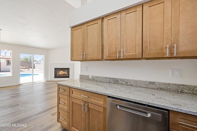 7112 S Haskins Dr, Tucson, AZ 85746 - kitchen featuring dishwasher, light wood-style floors, open floor plan, light stone counters, and a tile fireplace