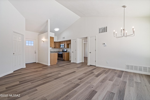 7112 S Haskins Dr, Tucson, AZ 85746 - unfurnished living room featuring a chandelier, high vaulted ceiling, light wood-type flooring, and baseboards