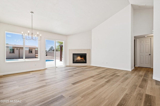7112 S Haskins Dr, Tucson, AZ 85746 - unfurnished living room with light wood finished floors, a chandelier, baseboards, and a fireplace
