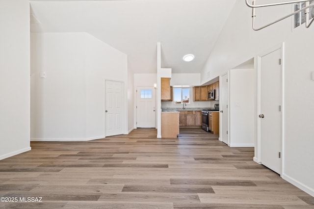 7112 S Haskins Dr, Tucson, AZ 85746 - kitchen with stainless steel appliances, open floor plan, a sink, brown cabinets, and light wood finished floors