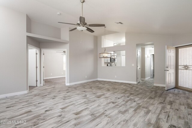 1542 N Amberbrooke Ave, Tucson, AZ 85745 - unfurnished living room featuring a ceiling fan, light wood-style floors, baseboards, high vaulted ceiling, and a chandelier