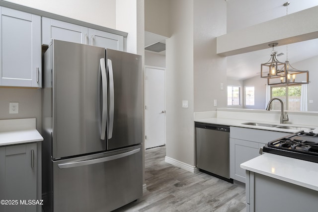 1542 N Amberbrooke Ave, Tucson, AZ 85745 - kitchen with appliances with stainless steel finishes, a sink, light wood-style flooring, decorative light fixtures, and light countertops