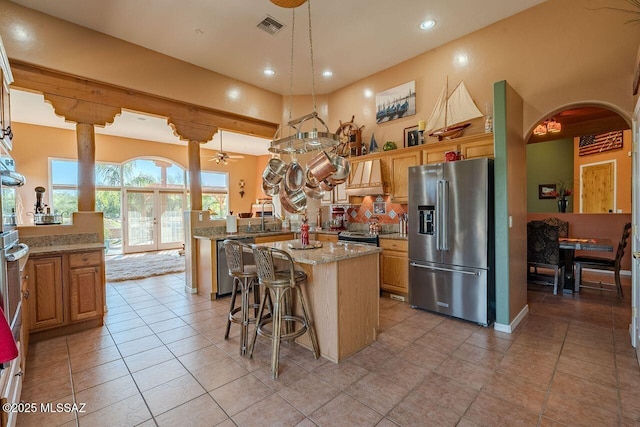 489 W Wedge Way, Green Valley, AZ 85614 - kitchen featuring appliances with stainless steel finishes, arched walkways, a peninsula, light stone countertops, and a kitchen island