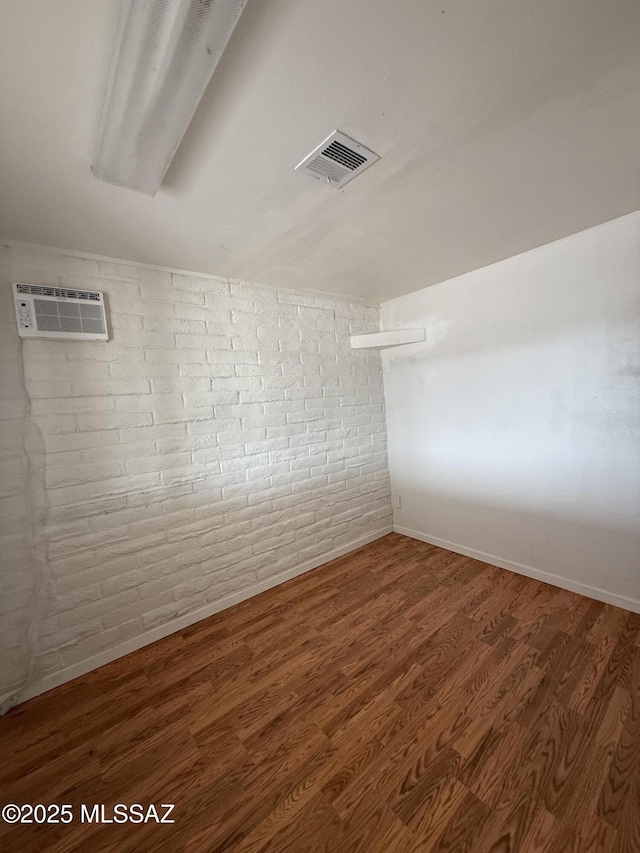 1036 W Michigan St, Tucson, AZ 85714 - unfurnished room featuring brick wall, wood finished floors, an AC wall unit, and baseboards