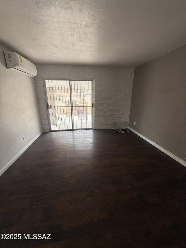 1036 W Michigan St, Tucson, AZ 85714 - spare room featuring a wall mounted AC, dark wood-style floors, baseboards, and a textured ceiling