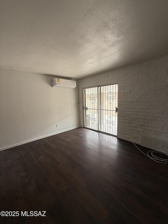 1036 W Michigan St, Tucson, AZ 85714 - spare room featuring a wall unit AC, dark wood-style floors, a textured ceiling, and baseboards