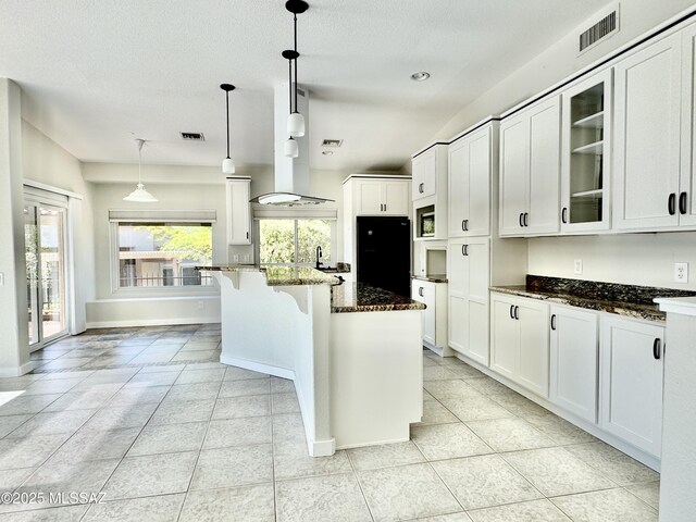 13942 N Cirrus Hill Dr, Oro Valley, AZ 85755 - kitchen featuring freestanding refrigerator, dark stone counters, glass insert cabinets, white cabinetry, and a textured ceiling