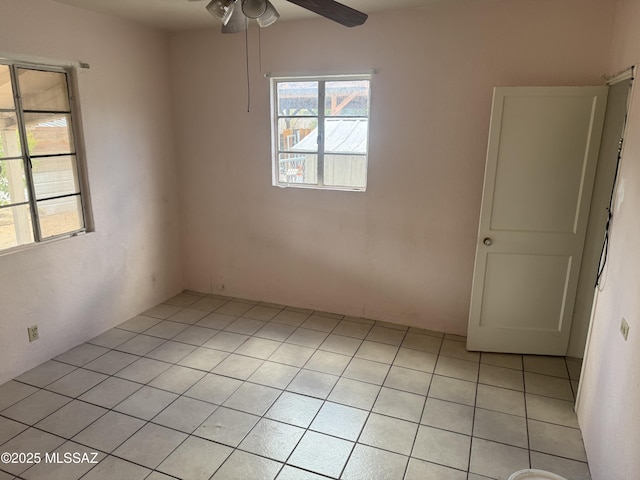 empty room with ceiling fan and light tile patterned floors