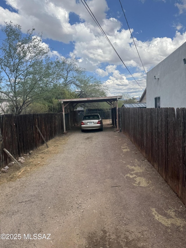 view of car parking featuring dirt driveway and a detached carport