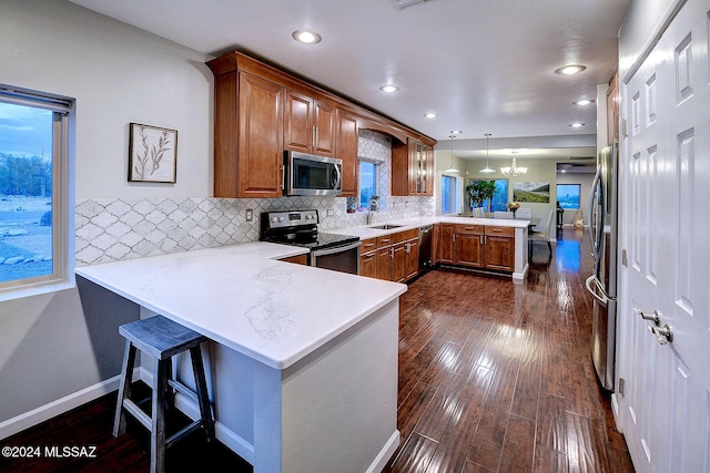 6631 N Camino Padre Isidoro, Tucson, AZ 85718 - kitchen with appliances with stainless steel finishes, a peninsula, brown cabinets, a sink, and recessed lighting