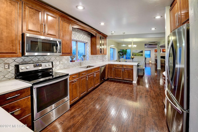 6631 N Camino Padre Isidoro, Tucson, AZ 85718 - kitchen with stainless steel appliances, a peninsula, a sink, a chandelier, and dark wood-type flooring