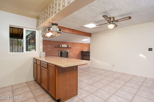2702 E Prince Rd, Tucson, AZ 85716 - kitchen featuring a peninsula, a fireplace, open floor plan, ceiling fan, and brown cabinetry