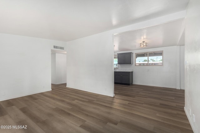 7433 E 19th St, Tucson, AZ 85710 - unfurnished living room featuring dark wood-style flooring and baseboards