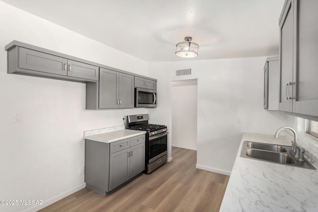 7433 E 19th St, Tucson, AZ 85710 - kitchen with appliances with stainless steel finishes, a sink, gray cabinets, and baseboards