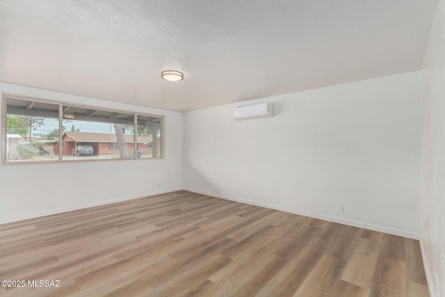 7433 E 19th St, Tucson, AZ 85710 - empty room with a wall unit AC, wood finished floors, and baseboards