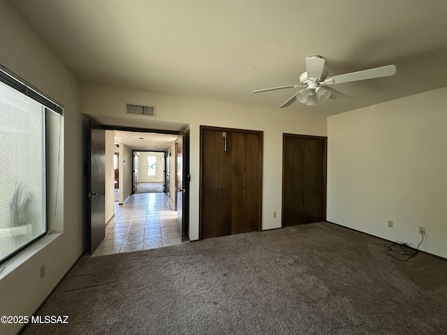 4241 E Aquarius Dr, Tucson, AZ 85718 - unfurnished bedroom with multiple closets, light colored carpet, light tile patterned floors, and ceiling fan